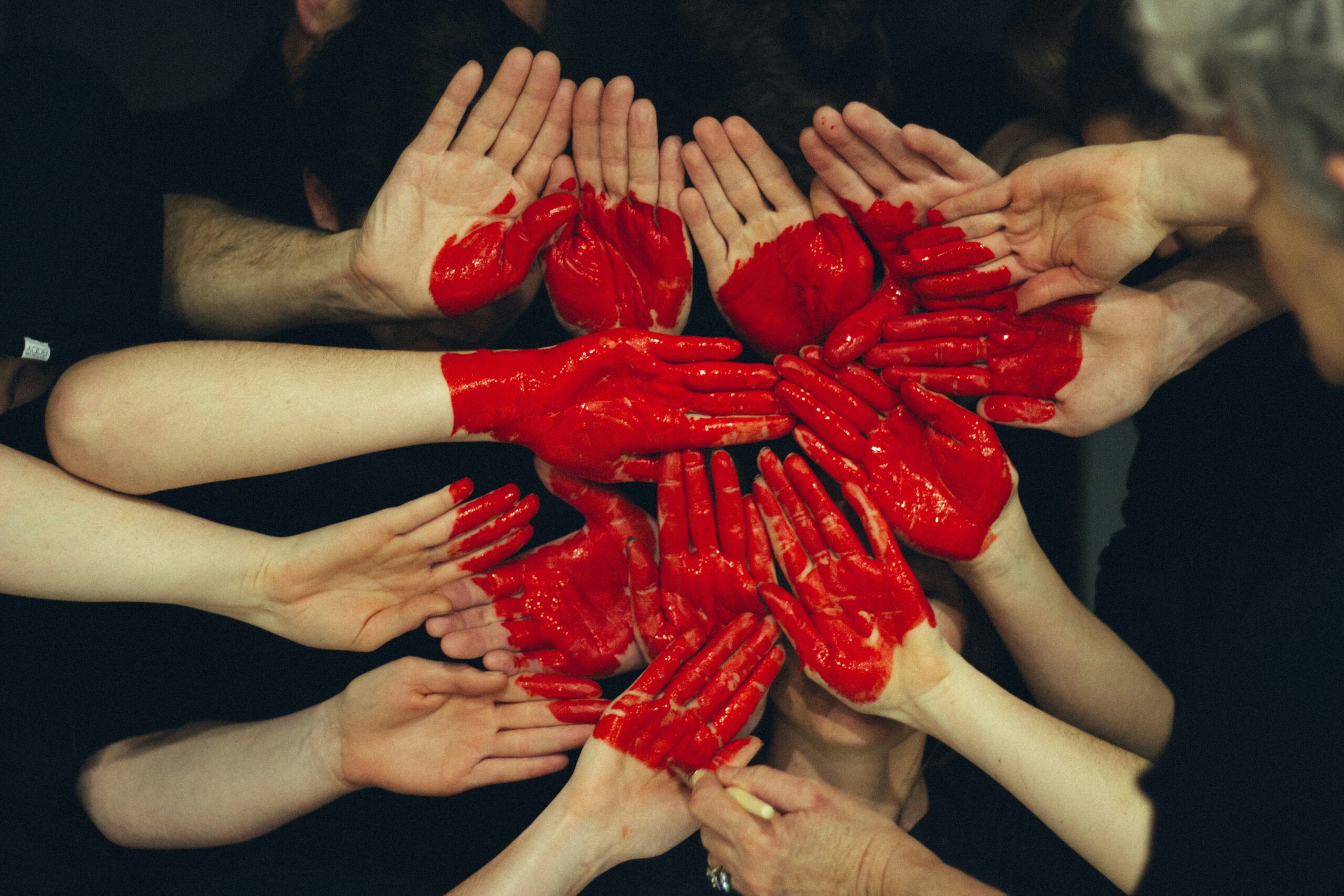 Mains peintes en rouge réunies pour former un cœur, symbole d'empathie