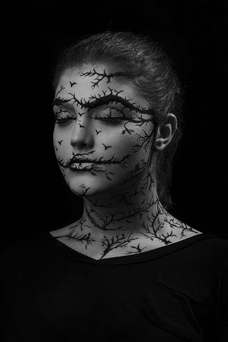 Portrait en noir et blanc d'une femme aux yeux fermés, le visage couvert de branches dessinées