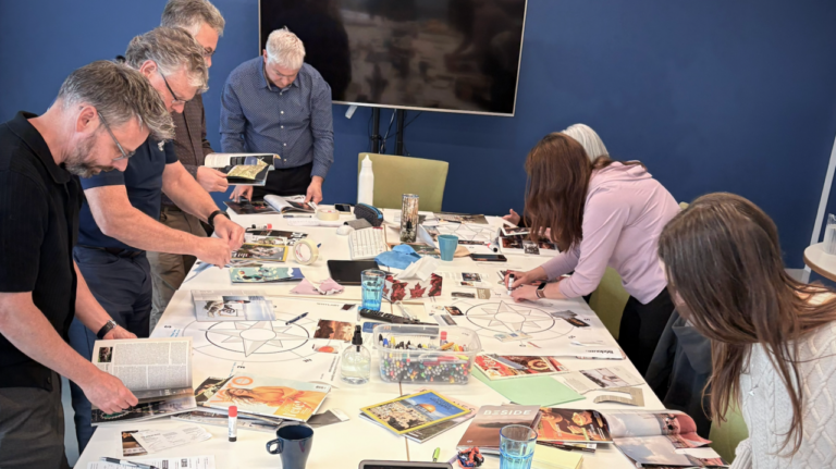 Gestionnaires penchés sur une table couverte de magazines et d'images, en atelier de cadres collaboratifs