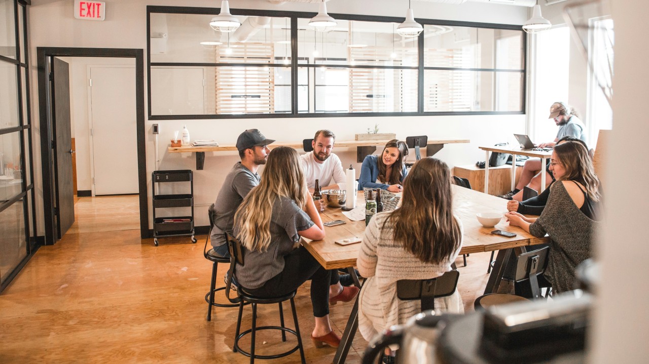 Équipe en atelier d'intelligence collective autour de tables, dans un espace de travail lumineux